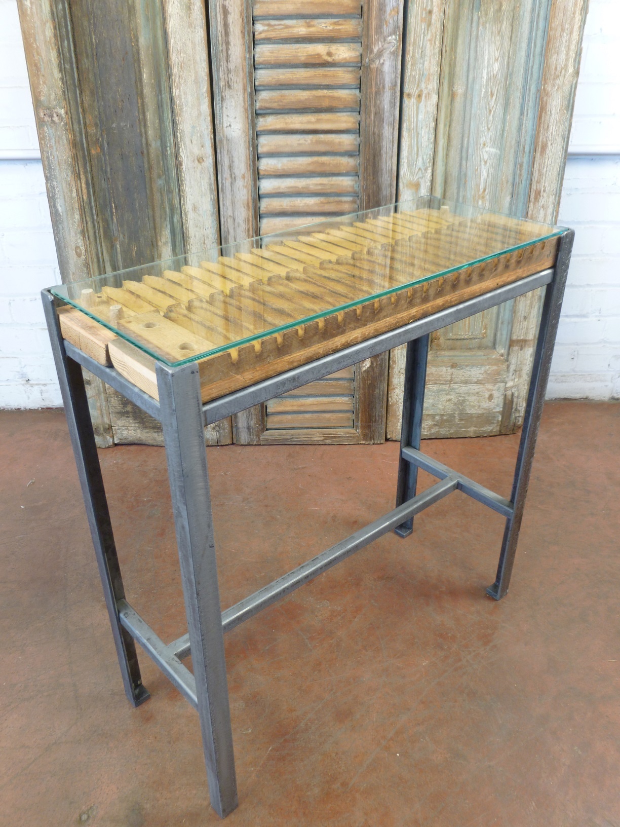 Ferro Designs LLC custom iron drink table featuring antique wood cigar molds, a steel base finish, and a glass top.