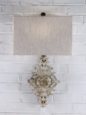 Medallion custom iron wall sconce with a white, distressed finish. Paired with a half rectangle linen lamp shade.